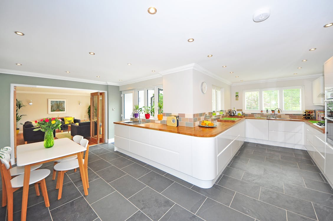 A kitchen featuring a wooden table surrounded by four chairs, with cabinets and appliances in the background.