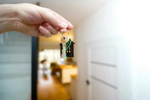 A person holding a key, symbolizing access to a new home.