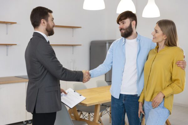 male real estate agent doing business showing house potential buying couple